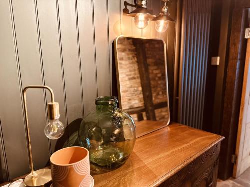 a glass vase on a wooden table with a mirror at Cobblers Cottage Brigg in Brigg