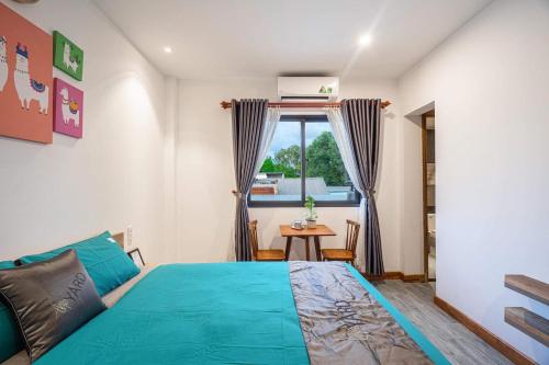 a bedroom with a blue bed and a table at THE YARD, DUONG DONG, PHU QUOC in Phu Quoc