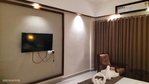 a room with a tv and a chair and a mirror at EZHIMALA AYURVEDA AND WELLNESS RESORT in Payyannūr