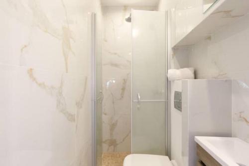 uma casa de banho branca com um chuveiro e um WC. em LE PETIT MARCHE - NEW 2021 Fabuleux studio 2Pax Wi-fi A/C em Antibes