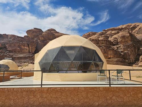 a building in the desert with mountains in the background at Kylie magic camp in Wadi Rum