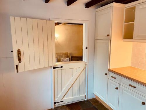 a kitchen with white cabinets and a large mirror at Bewdley Central - Sandy Bank Cottage in Bewdley