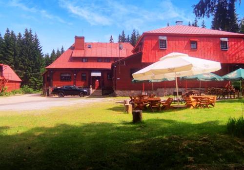 a red barn with tables and an umbrella in front of it at Gospoda Graniczna Bombaj Jakuszyce in Szklarska Poręba
