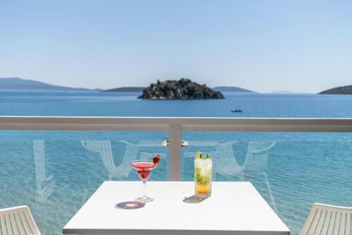 a table with two glasses and a view of the ocean at Nelly's Apartments in Tolo