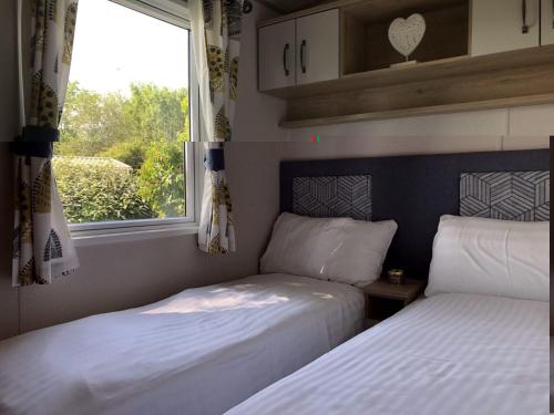 two beds in a small room with a window at Newbeach Holiday Park - Greenfields in Dymchurch
