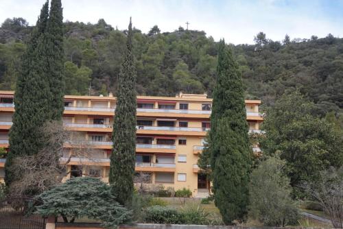 un bâtiment avec deux grands arbres devant lui dans l'établissement Amelie les Bains Coquet F1, à Amélie-les-Bains-Palalda