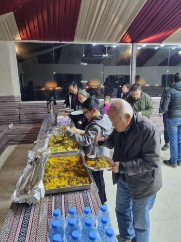 a group of people standing around a table eating food at Kylie magic camp in Wadi Rum