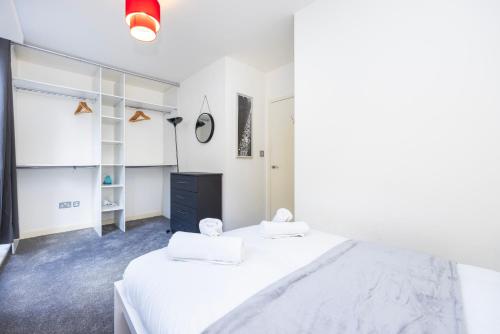 a white bedroom with two beds and a black dresser at Modern 1 BR Apartment Near Shoreditch - 10 Min Walk in London