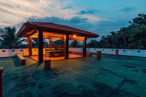 a gazebo with a table in the water at night at Villa Talpe in Talpe