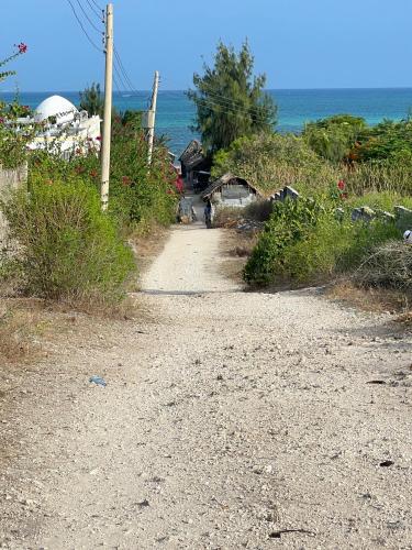 a dirt road next to the ocean on a beach at BeB Sardegna2 Anjumasa village in Watamu