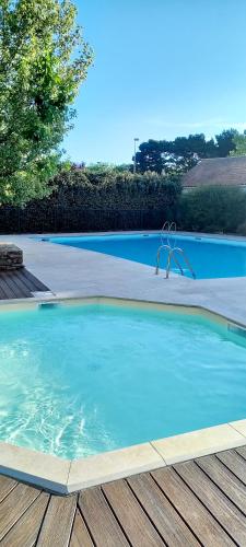 une grande piscine bleue avec une terrasse en bois dans l'établissement 3 pièces proche plage commerces et golf, à Pornic