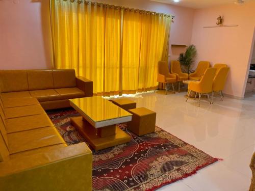 ウダイプールにあるRoyal Rajvilas Heightsのリビングルーム(黄色のカーテン、ソファ、椅子付)