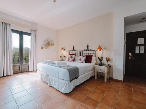 Un dormitorio con una gran cama blanca y una ventana en Hotel Boutique Cerro del Sol en Cenes de la Vega