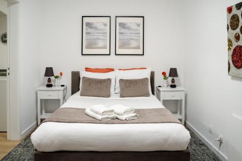 una camera da letto con un grande letto bianco con due tavoli di Porto Ribeira RC Traseiras a Porto