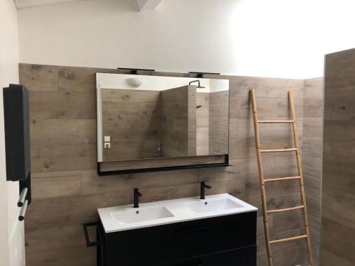 a bathroom with a sink and a mirror and a ladder at Charmante maison avec jacuzzi. in La Flotte