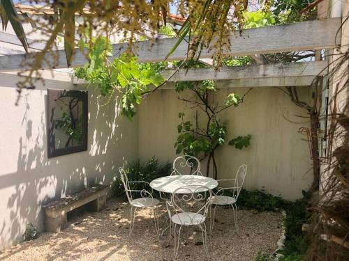 a table and chairs sitting under a wooden pergola at Charmante maison avec jacuzzi. in La Flotte