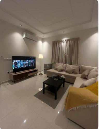 een woonkamer met een bank en een flatscreen-tv bij شقة حي العقيق غمام in Riyad
