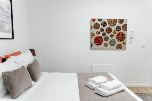 een slaapkamer met een wit bed en een schilderij aan de muur bij Porto Ribeira RC Traseiras in Porto