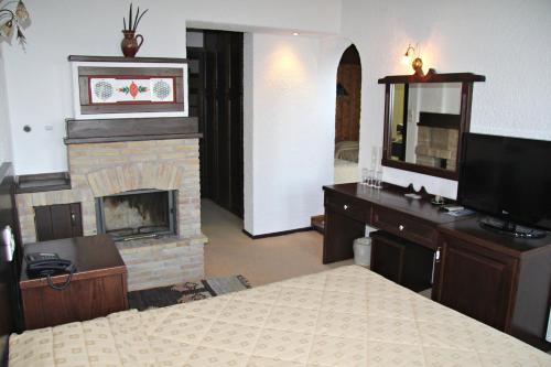 a bedroom with a fireplace and a bed and a television at Hotel Taxiarches in Aristi