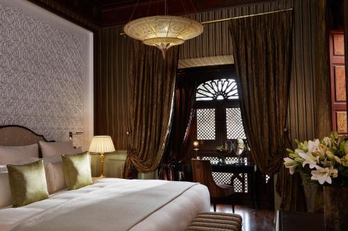 a bedroom with a large bed and a chandelier at Royal Mansour Marrakech in Marrakech