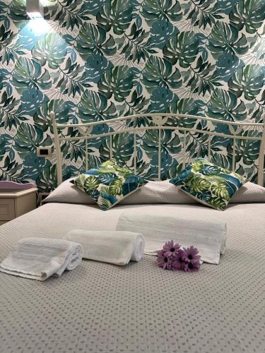 a bed with two towels and purple flowers on it at Villa Primofiore di Vendicari in La Banca