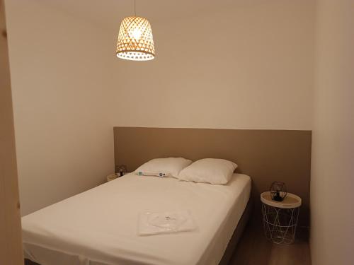 Cette chambre comprend un lit avec des draps blancs et une lampe. dans l'établissement Appartement au coeur de la station, à Les Déserts