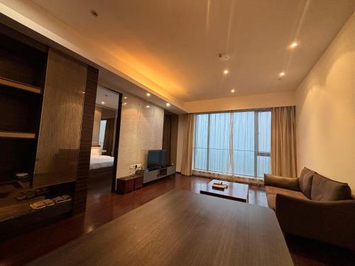 a living room with a couch and a large window at Guangzhou City Inn Hotel Apartment Pazhou in Guangzhou