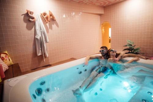 Un uomo e una donna seduti in una vasca da bagno di Casa Mila & SPA- Chambres d'Hôtes raffinées vue Loire et piscine a Saint-Mathurin