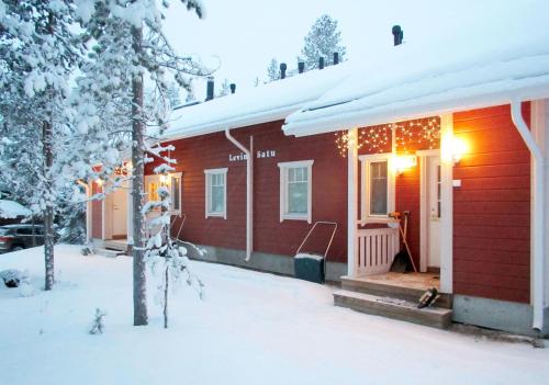 a red house in the snow with christmas lights at LevinSatu: SeLevi and TaLevi Apartments in Levi