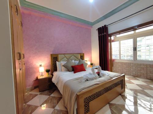 - une chambre avec un grand lit aux murs roses dans l'établissement Aljazeera apartment, à Tanger