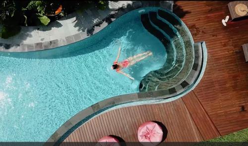 un hombre nadando en una piscina en una piscina en Odessa Village by Pramana Villas en Gianyar