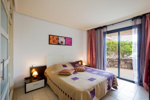 a bedroom with a bed and a sliding glass door at Balcon De Los Gigantes in Puerto de Santiago