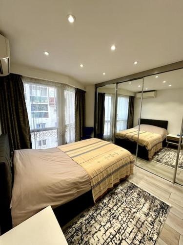 une chambre avec deux lits et un grand miroir dans l'établissement Spacieux et Élégant Appartement - Boulogne - Paris, à Boulogne-Billancourt