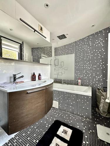 une salle de bain avec un lavabo et une baignoire dans l'établissement Spacieux et Élégant Appartement - Boulogne - Paris, à Boulogne-Billancourt