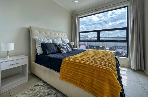 1 dormitorio con 1 cama y ventana grande en StayEasy Lux Apartment, en Edenvale
