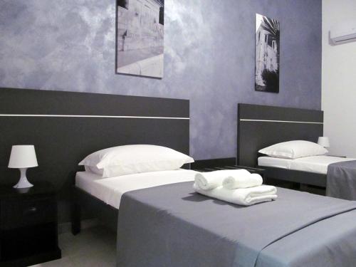Trinacria House - Appartamento Deluxe Comiso في كوميزو: سريرين في غرفة مع جدران أرجوانية