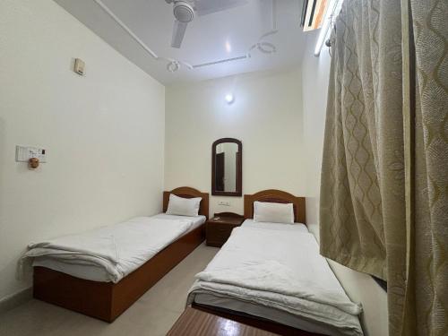 two beds in a room with a mirror at Lucky Guest House Bodhgaya in Bodh Gaya