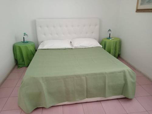 a bedroom with a large bed with two green tables at Terrazza Faraglioni in Acitrezza