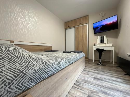 Schlafzimmer mit einem Bett, einem Schreibtisch und einem TV in der Unterkunft Апартамент Божур in Warna