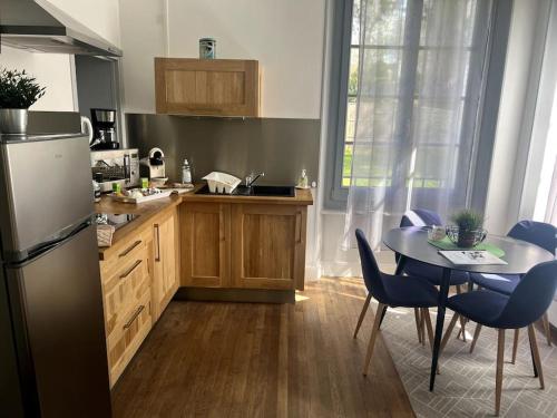 une cuisine avec une table, des chaises bleues et une table. dans l'établissement Résidence Harmonie Appartement N 2 Meublé Avec Petit Déjeuner, à Néris-les-Bains