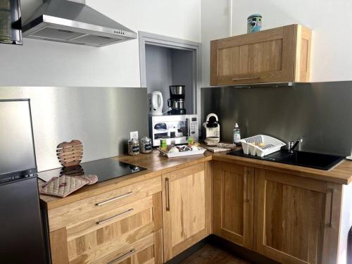 une cuisine avec des armoires en bois et un réfrigérateur noir dans l'établissement Résidence Harmonie Appartement N 2 Meublé Avec Petit Déjeuner, à Néris-les-Bains