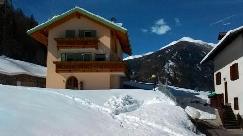 ein Haus im Schnee vor einem Berg in der Unterkunft Ferienwohnung für 6 Personen ca 75 m in Pellizzano, Trentino Val di Sole in Trient