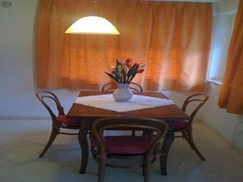 einen Tisch mit zwei Stühlen und eine Vase mit Blumen darauf in der Unterkunft Ferienwohnung für 6 Personen ca 75 m in Pellizzano, Trentino Val di Sole in Trient