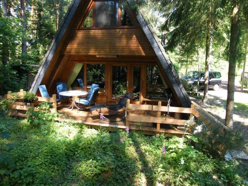 una cabaña en el bosque con mesa y sillas en Nurdachferienhaus in ruhiger Lage, auf einem naturbelassenem Grundstück mit nahegelegener Angelmöglichkeit - b48731, en Wienhausen