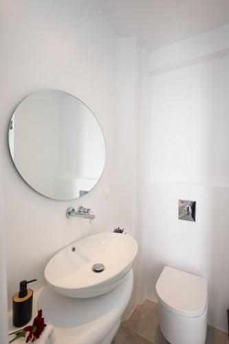 a white bathroom with a toilet and a mirror at Myconian Little Venice Elite Suites with Sea View in Mýkonos City