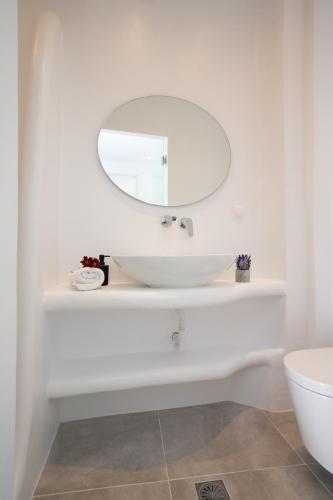 a white bathroom with a sink and a mirror at Myconian Little Venice Elite Suites with Sea View in Mýkonos City