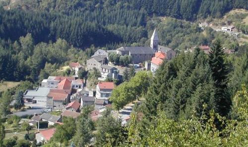 eine Gruppe von Häusern auf einem Hügel mit einer Kirche in der Unterkunft Grande maison au coeur du parc naturel des Monts d'Ardèche in Saint-Julien-Boutières