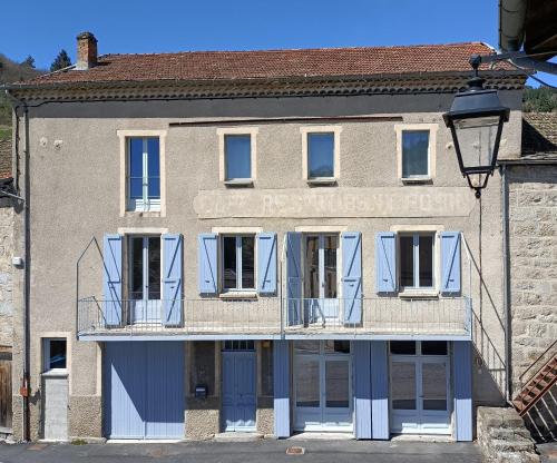 ein Gebäude mit blauen Türen und einem Balkon in der Unterkunft Grande maison au coeur du parc naturel des Monts d'Ardèche in Saint-Julien-Boutières