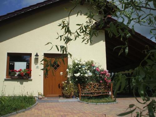 a house with a wooden door and a bench with flowers at Ferienhaus in Kienitz mit Grill, Terrasse und Garten in Letschin