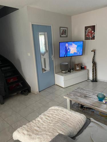 un salon avec une télévision et une table dans l'établissement Maison au calme, à Avignon